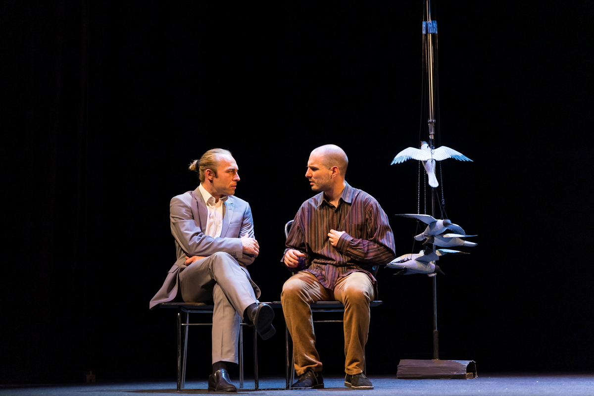 Scena ze sztuki, dwóch mężczyzn siedzi rozmawiając.