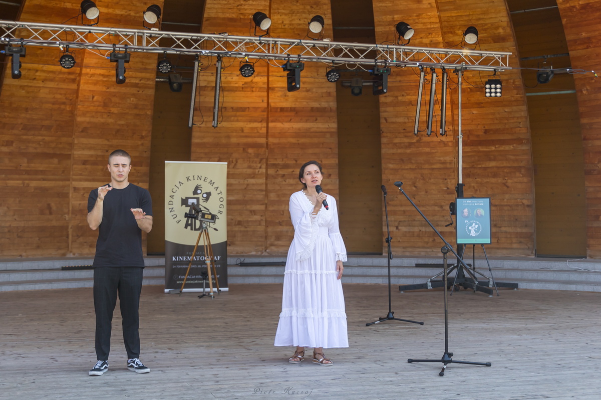 Otwarcie imprezy, na scenie Anna Czapnik-Wójcik i tłumacz języka migowego. W tle rollup Fundacji Kinematograf.