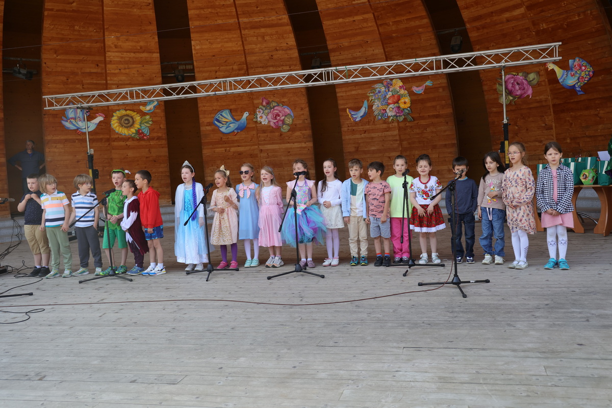 Grupa dzieci śpiewa na scenie.