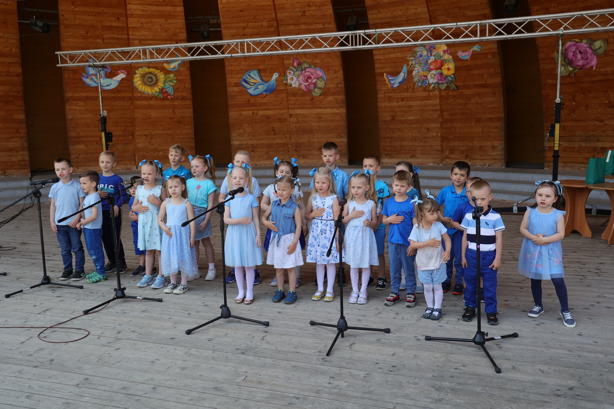 Grupa przedszkolaków, ubrane są w biało-niebieskie stroje.