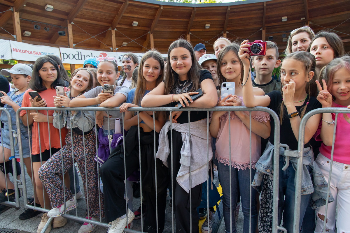 Młodzi widzowie przy barierce podczas koncertu.