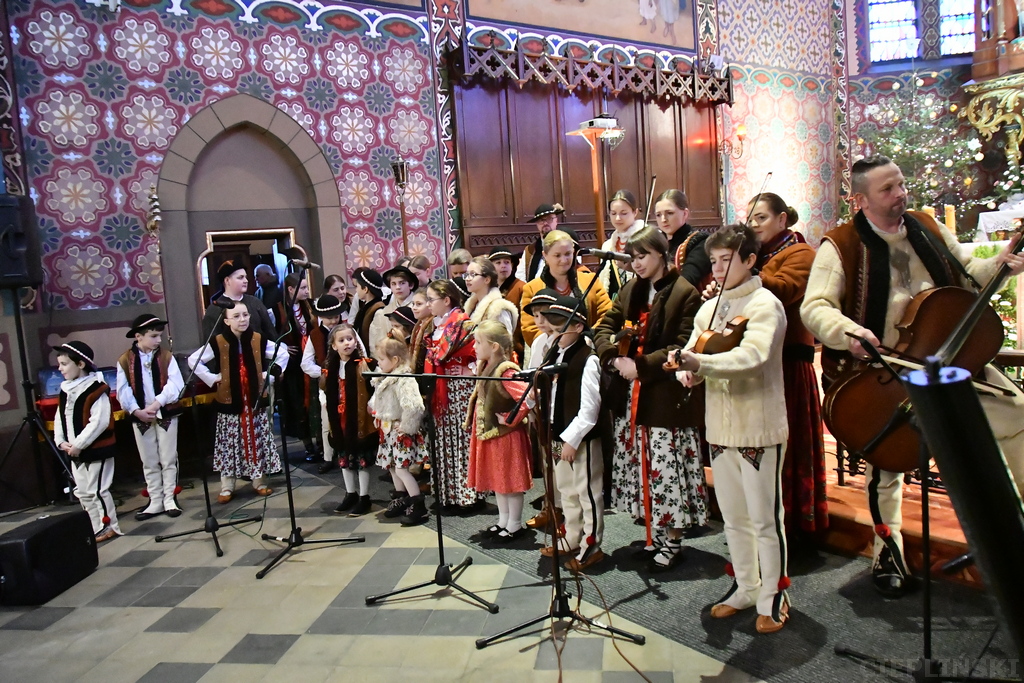Zespół ludowy złożony z dzieci i dorosłych podczas koncertu w kościele.