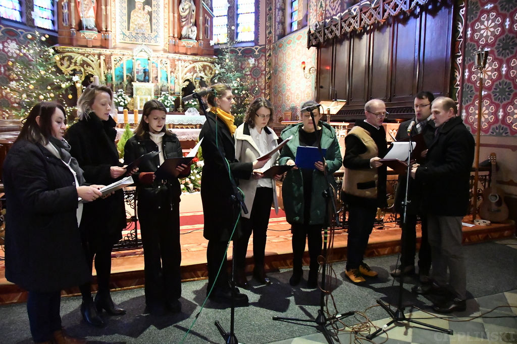 Zespół złożony z sześciu kobiet i trzech mężczyzn śpiewa ze śpiewników.